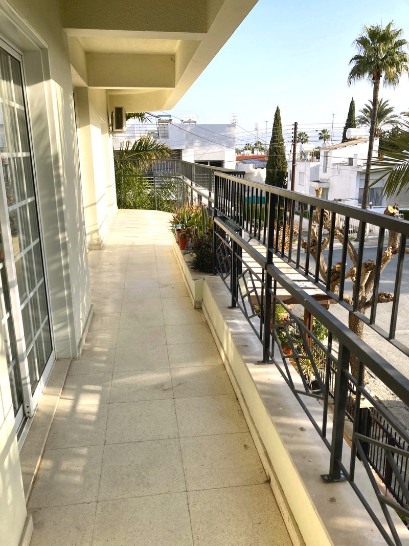 Long covered balcony running the length of the apartment with a green, leafy outlook