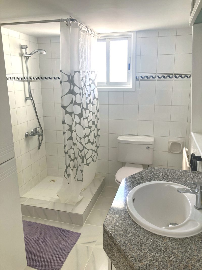 Bathroom with a large glazed walk-in shower and neutral tiling