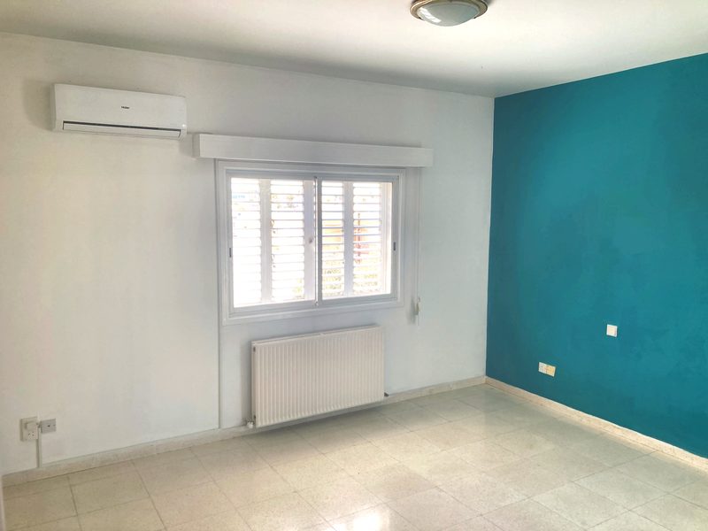 Bedroom with a teal accent wall, air conditioning unit and a central-heating radiator