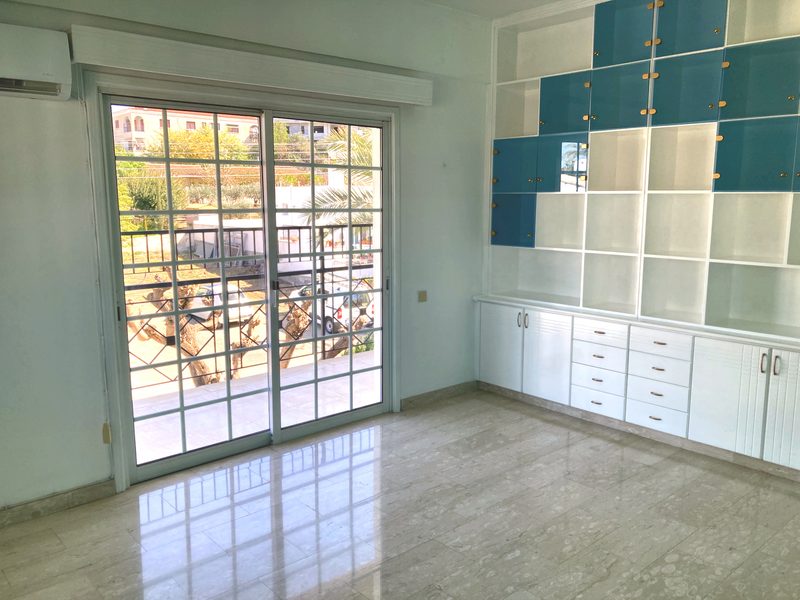 Room with built-in shelving and cupboards and a door opening onto the balcony