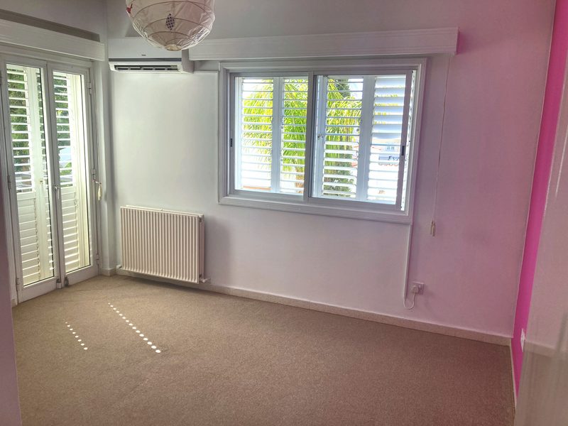 Fourth bedroom with a soft pink wall, suitable as a child's room or study