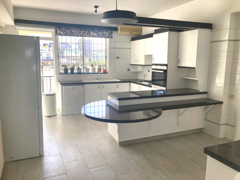 Fitted kitchen with white units, granite breakfast bar, oven and large fridge-freezer
